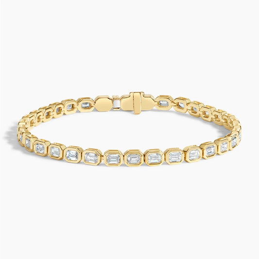 Gold tennis bracelet with emerald-cut diamonds in bezel settings on white background