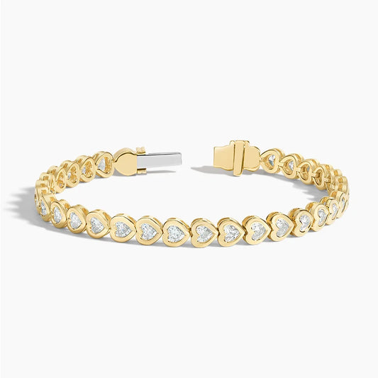 Yellow gold tennis bracelet with heart-shaped settings and lab-grown diamonds on white background