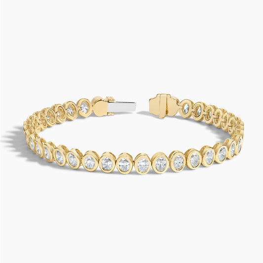 Yellow gold tennis bracelet with oval lab-grown diamonds in bezel settings on white background