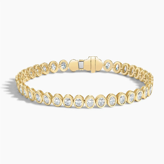 Yellow gold tennis bracelet with oval-shaped lab-grown diamonds on white background