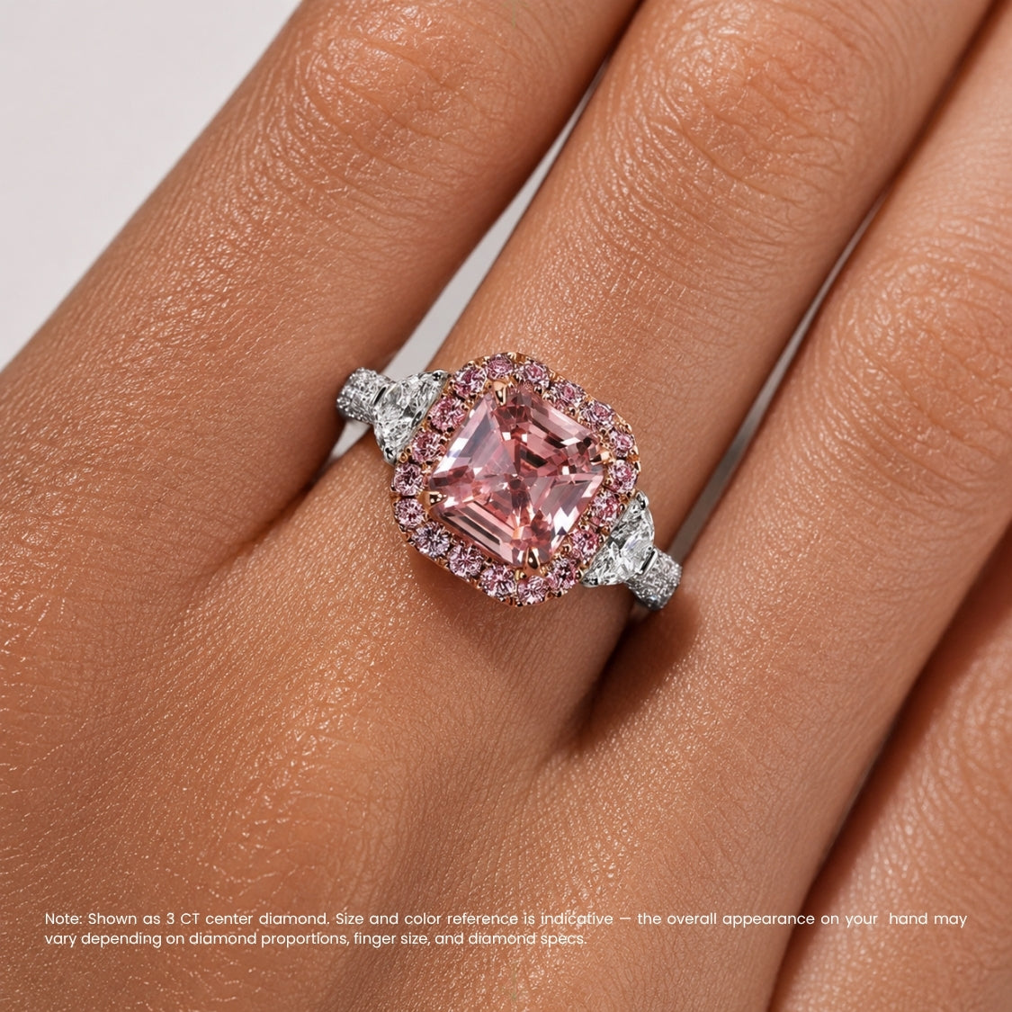 A close-up of a ring worn on a finger, featuring a large rectangular pink gemstone surrounded by a halo of small pink and clear stones, with additional small side stones on a silver-toned band. A note at the bottom explains the size and color reference of the center stone.