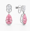 A pair of high-end drop earrings featuring a large pink pear-cut diamond and a smaller round diamond in a silver-toned setting, shown on a clean white background.