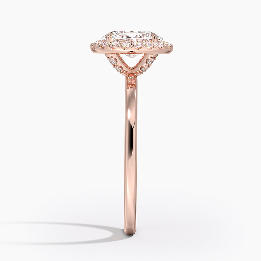 Side view of rose gold oval halo diamond engagement ring with pavé band