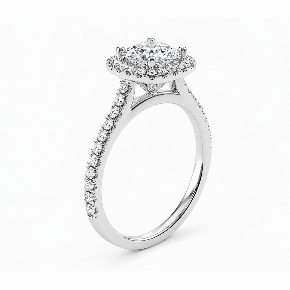 A silver-toned halo ring featuring a round-cut center stone surrounded by a double halo of smaller stones, with a pavé-set shank, shown on a clean white background.