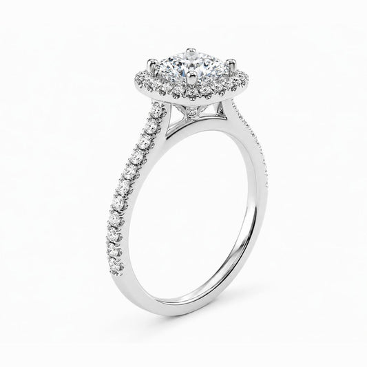 A silver-toned halo ring featuring a round-cut center stone surrounded by a double halo of smaller stones, with a pavé-set shank, shown on a clean white background.