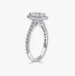 A silver-toned diamond engagement ring featuring a round-cut center stone in a halo setting, with pavé diamond accents along the shank, shown on a light gray background.