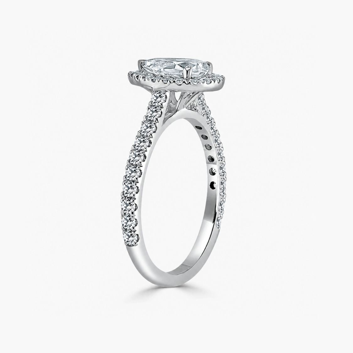 A silver-toned diamond engagement ring featuring a round-cut center stone in a halo setting, with pavé diamond accents along the shank, shown on a light gray background.