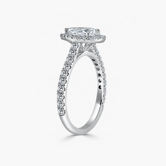 A silver-toned diamond engagement ring featuring a round-cut center stone in a halo setting, with pavé diamond accents along the shank, shown on a light gray background.