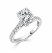A radiant cut diamond engagement ring in a polished white gold or platinum setting, featuring a halo of small pavé diamonds along the shank, shown on a clean white background.